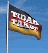 a flag that says " tidak takut " is waving in the wind