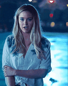a woman in a white shirt is standing in front of a blue pool