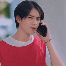 a man in a red shirt is talking on a cell phone .