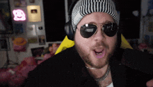 a man wearing sunglasses and a beanie with the letter a on it