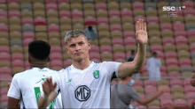 a soccer player wearing a green shirt with a mc logo on it