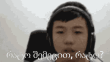 a young boy wearing headphones is looking at the camera with a question in another language