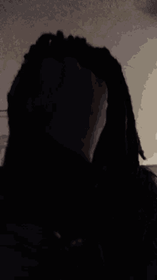 a person in a hooded jacket is standing in the dark