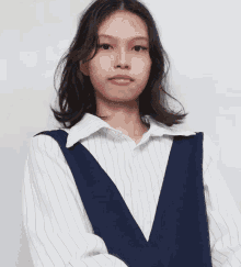a woman wearing a blue vest and a white striped shirt