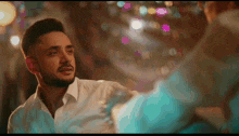 a man in a white shirt looks at his reflection in a mirror