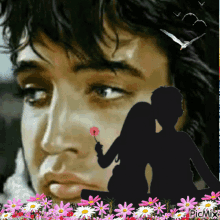 a silhouette of a man and a woman with flowers in the foreground