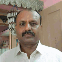 a man with a mustache is standing in front of a door