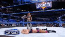 a woman is laying on the ground in a wrestling ring with a sign that says wrestlemania