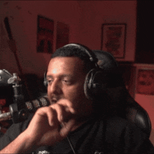 a man wearing headphones is sitting in front of a microphone with a red background