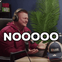 a man wearing headphones is sitting in front of a microphone and says nooooo