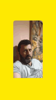 a man with a beard is posing for a picture in front of a painting