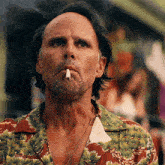 a man smoking a cigarette and wearing a shirt with pine trees on it