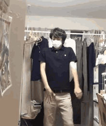 a man wearing a mask is standing in a room with clothes hanging on a rack
