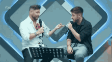 two men are sitting in front of microphones with rtve written on the bottom right