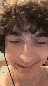 a young man with curly hair is wearing headphones and making a funny face
