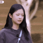 a woman with long black hair is wearing a gray sweater and a blue strap