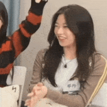 a woman is sitting at a table with her hands in the air and smiling .