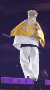 a man is standing on a stage holding a yellow scarf .