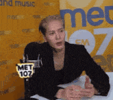 a man is sitting in front of a microphone with a met 107 sign on it