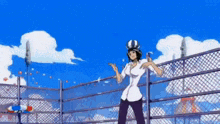 a woman in a helmet is standing next to a fence .