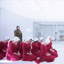 a group of women in red dresses are kneeling down