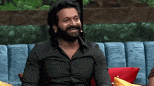 a man with a beard is sitting on a blue couch .