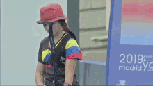a woman in a red hat is holding a bow and arrow in front of a sign that says 2019 world madrid
