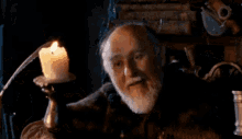 a man with a beard is laying down in front of a candle