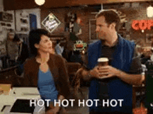 a man and a woman are standing next to each other in a restaurant holding cups of coffee .
