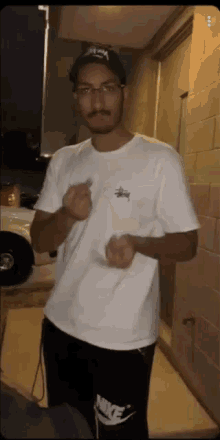a man wearing a white stussy shirt and black nike pants