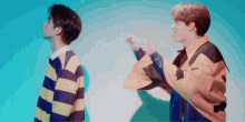 two young men are standing next to each other and one of them is wearing a yellow jacket