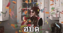 a woman is standing in a kitchen surrounded by confetti and sticky notes .