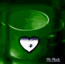 a green cup with a heart and an ant in it