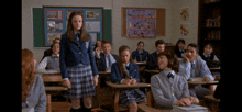 a girl in a school uniform stands in a classroom