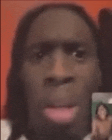 a close up of a man 's face with a woman 's face in the background .