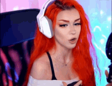 a woman with red hair is wearing headphones and a bra while sitting in a chair .