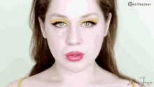 a close up of a woman 's face with a yellow eyeshadow and red lips