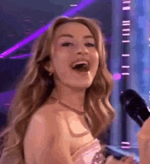 a woman is singing into a microphone while standing in front of a stage .