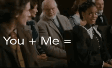a group of people are sitting in a room with the words `` you + me = '' written in white letters .