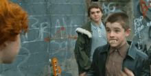 a young boy with vampire teeth is talking to another boy