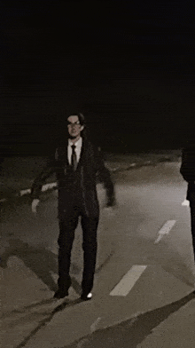 a man in a suit and tie is walking down a street