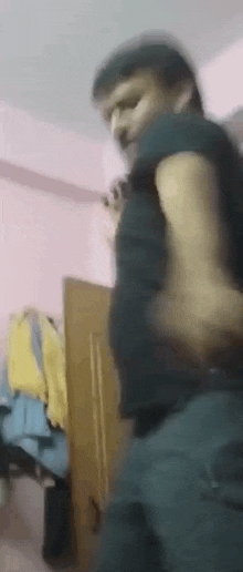 a man in a black shirt is standing in a room with his hands on his hips .