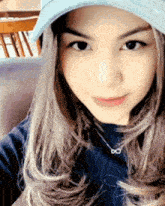 a woman wearing a blue hat and a necklace with the infinity symbol