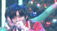 a man in a red jacket is singing into a microphone .