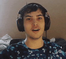 a young man wearing headphones looks at the camera