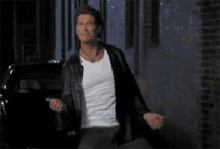 a man in a leather jacket and a white shirt is dancing