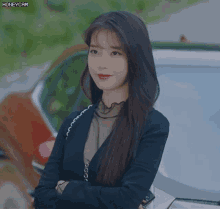 a woman stands in front of a car with her arms crossed and the words honeycam visible