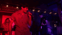 a man singing into a microphone while another man plays a guitar in a dark room