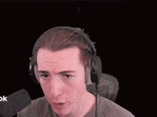 a man wearing headphones and a microphone is covering his face with his hand