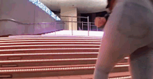 a person is walking down a set of stairs that are lit up with lights .